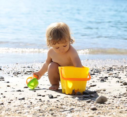 Enfant jouant dans le sable avec un saut jaune à la mer