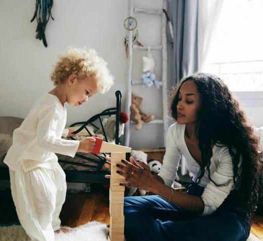 Enfant debout jouant avec sa maman au kapla en bois