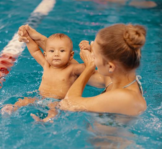 Bébé dans une piscine tenu dans les mains par une femme