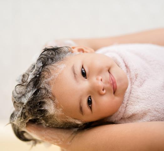 Visage enfant qui sourit avec les cheveux mouillés qui moussent